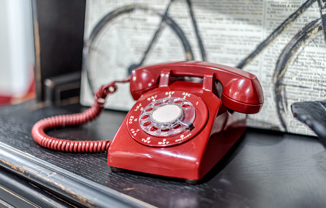 A classic red rotary phone on a table